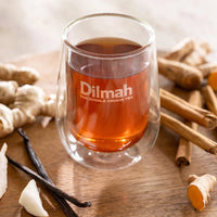 Glass of Dilmah tea with spices on a wooden surface